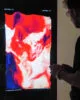 Digital Art Display Systems: Interactive digital art installation by Steve Zafeiriou displayed on an OLED screen, featuring vibrant red and white abstract visuals with frequency controls, showcasing innovative immersive art technology