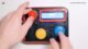 Hands playing on a DIY Arduino-based arcade console with joystick, buttons, and an LCD screen displaying game graphics.