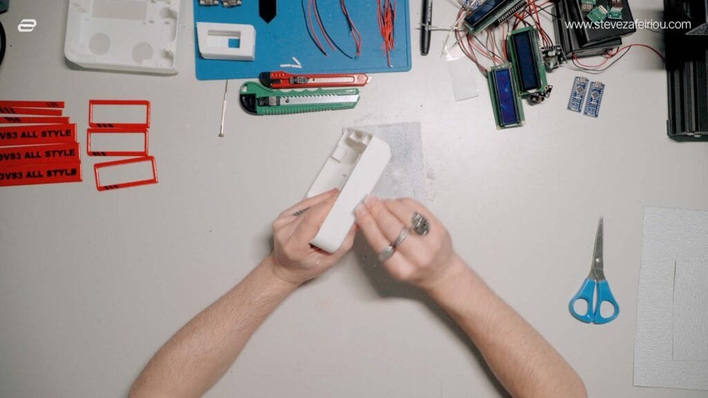 Smoothing a 3D-printed arcade console model using sandpaper, refining details for a high-quality retro gaming console build.